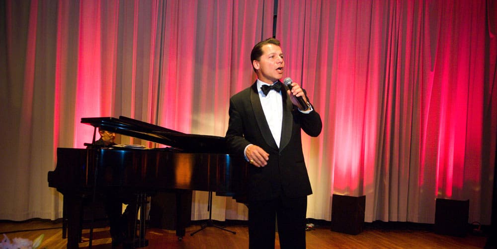 Male singer in a tux with a piano player on stage during a live event