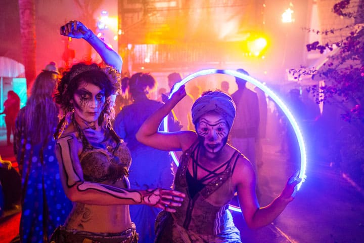 Women with skull makeup and a hula hoop LED light enjoying the festive activities of an outdoor event