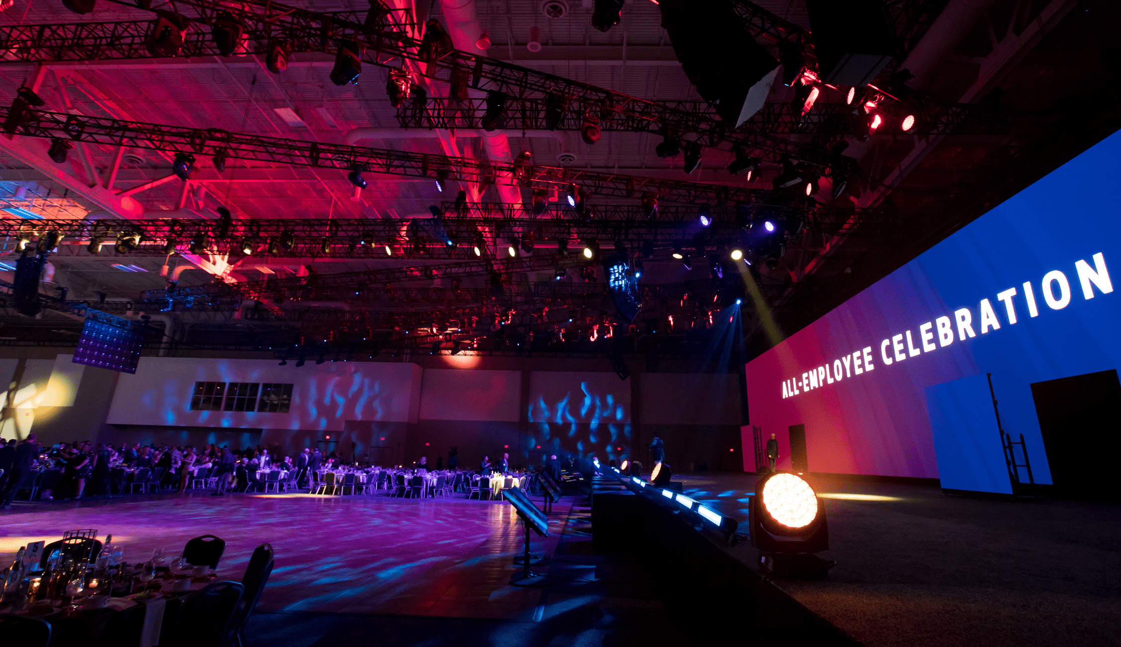 An All-Employee Celebration event in a venue with blue, purple, and red lighting