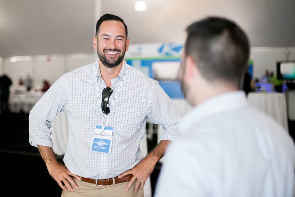 Happy person smiles with hands on hips at a business tradeshow event or vendor event.