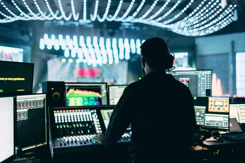 Male event production professional operates audio/visual equipment during a large corporate event.