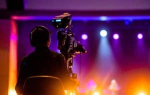 Event production crew member operates a camera recording the stage at a corporate event.